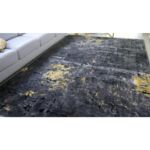 Textured abstract rug with gold, charcoal, and yellow pattern, featuring a black lower pile.