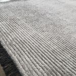 High-quality Mystique rug in silver gray tones with textured stripes and black tassels.