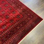 Machine-made red Bokhara rug with classic oriental patterns