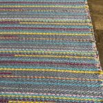 Turkish kilim carpet with striped designs in blue, pink, yellow, turquoise, maroon, and gray